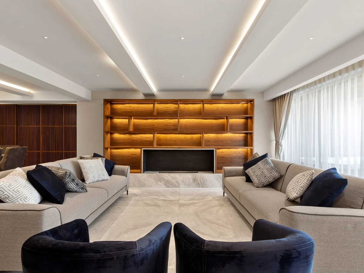 D67, private project: living room with a lit wooden bookcase and ceilings with indirect lighting.