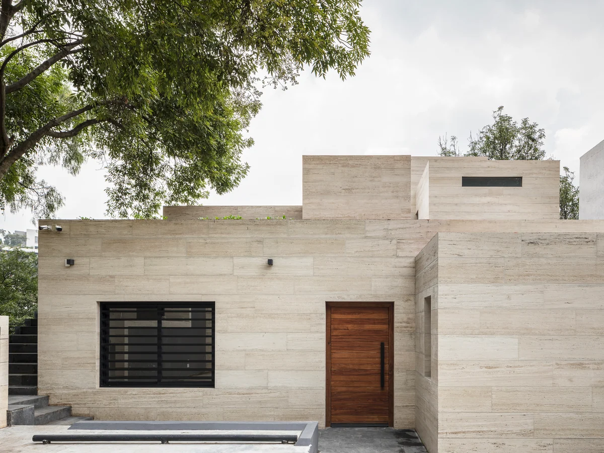 F153, private project: house with a travertine facade and a wooden door.