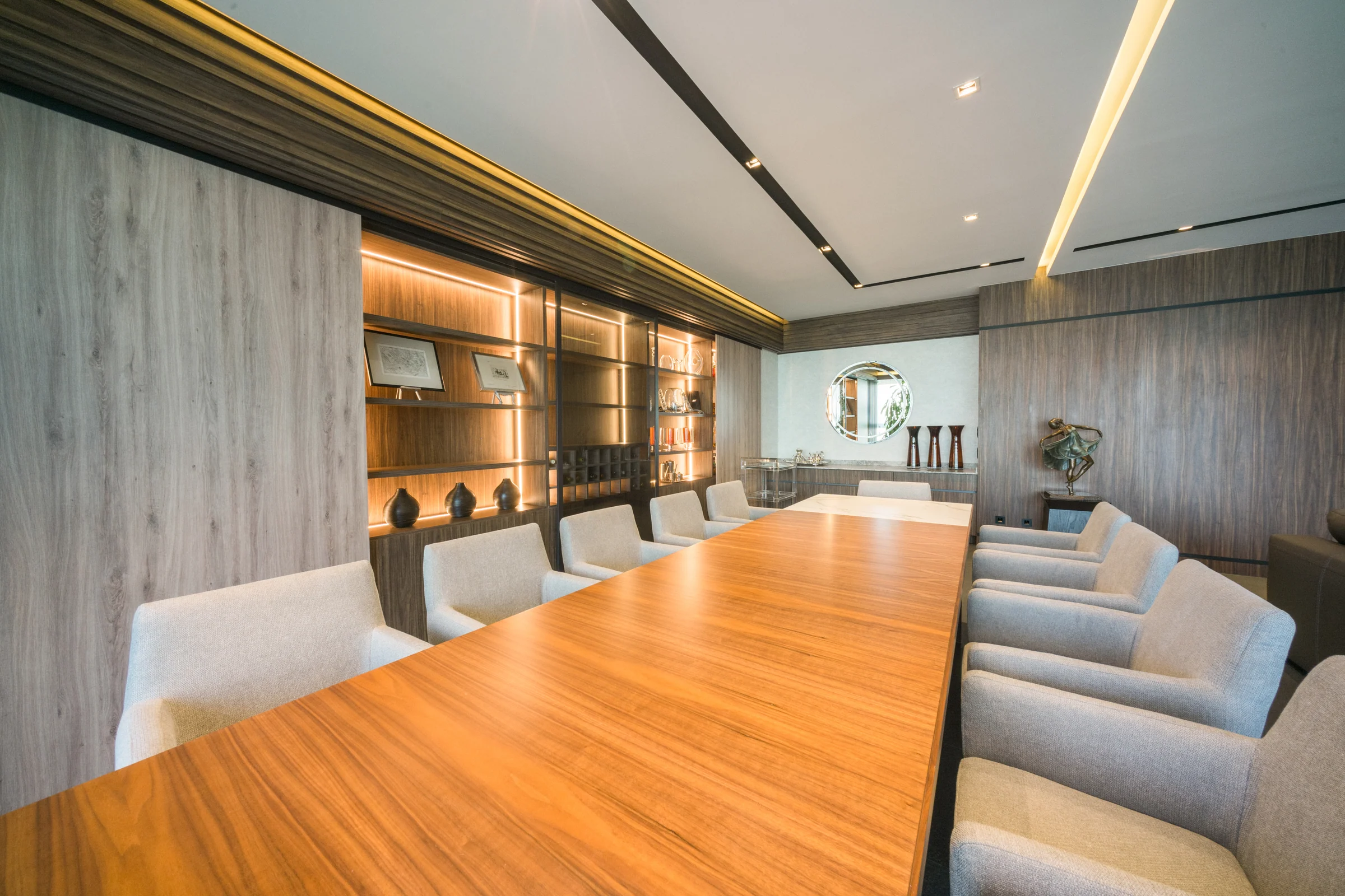 Finished meeting room with a wooden table and an illuminated wood wall.